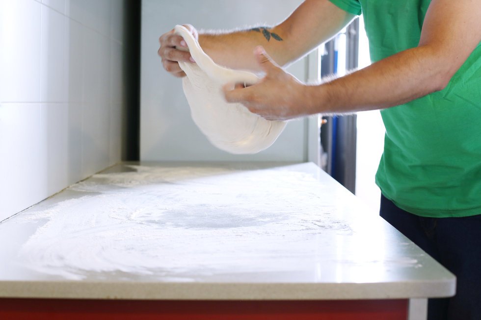 Hand-stretching fresh pizza dough in our kitchen